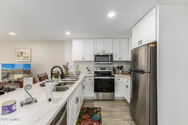 a kitchen with stainless steel appliances a refrigerator sink and white cabinets