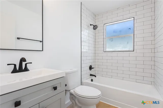 a bathroom with a bathtub shower sink vanity mirror and toilet
