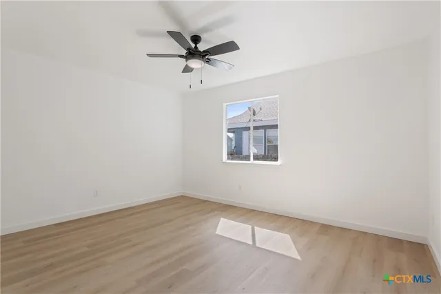 an empty room with a window and a fan