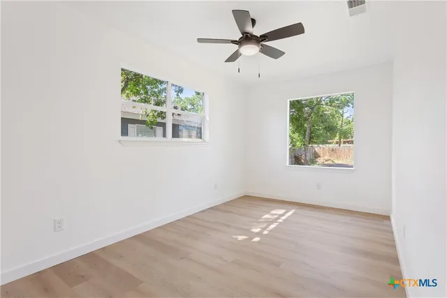 an empty room with a window and a fan