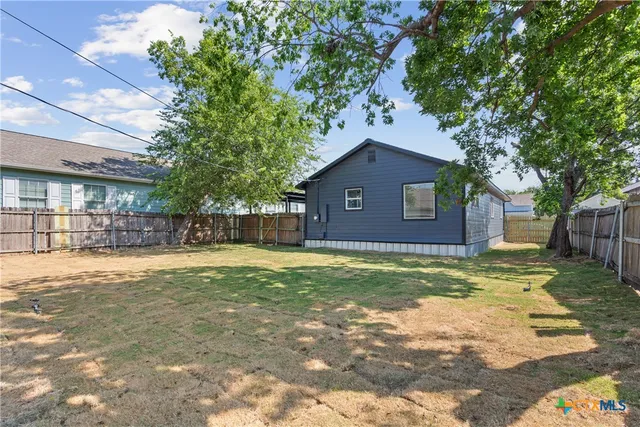 a view of a yard in front of a house with a large tree