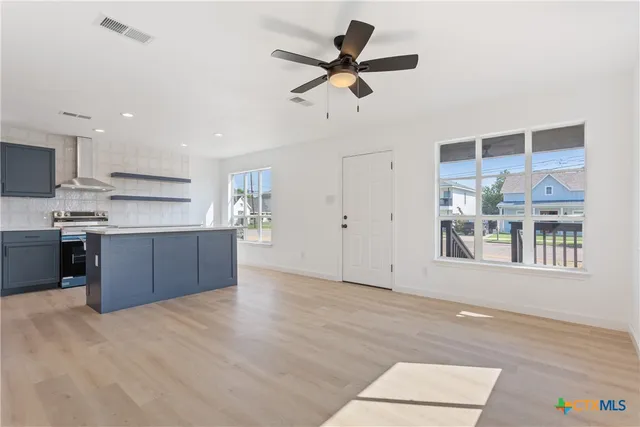 a view of kitchen with stainless steel appliances wooden floor and window