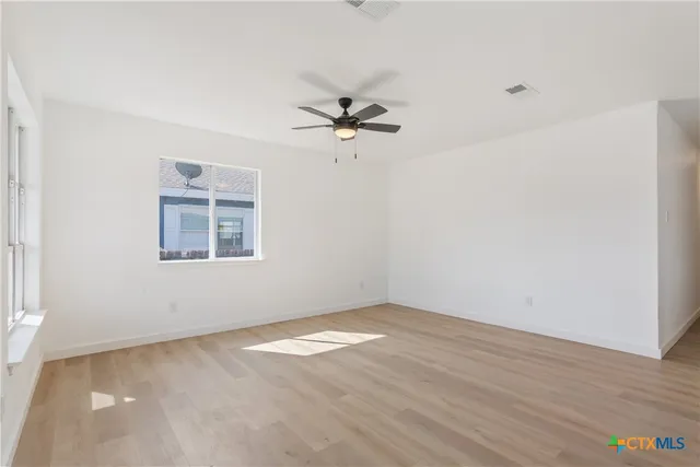 an empty room with a window and a ceiling fan