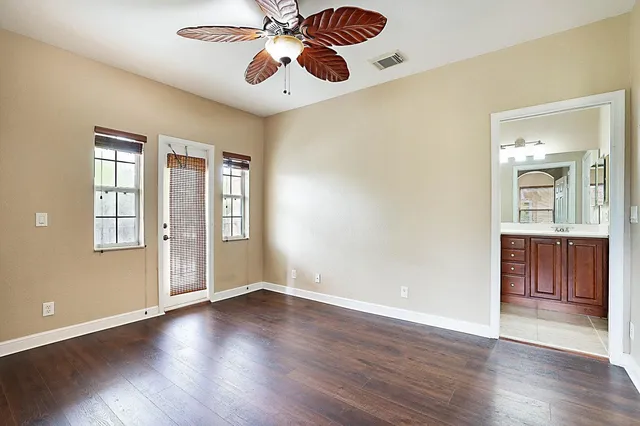 an empty room with windows and ceiling fan