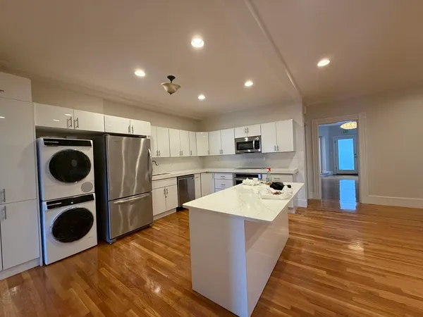 a large kitchen with kitchen island a stove a sink dishwasher and wooden cabinets with wooden floor