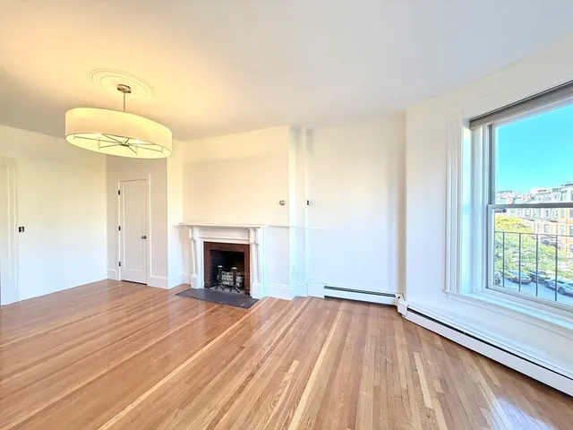 a view of empty room with wooden floor and fireplace