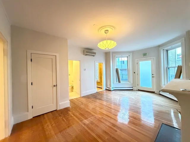 a view of an empty room with window and wooden floor