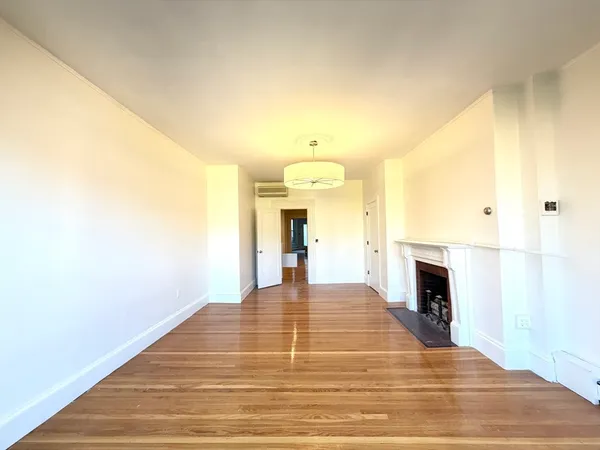 a view of empty room with wooden floor and fireplace