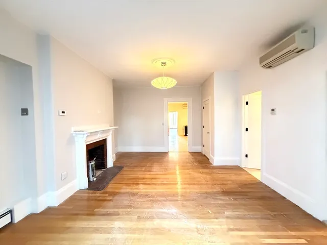 a view of empty room with wooden floor and fireplace