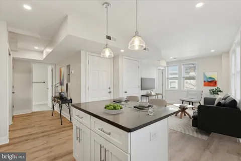 a open kitchen with stainless steel appliances granite countertop a stove a sink dishwasher and a dining table with wooden floor