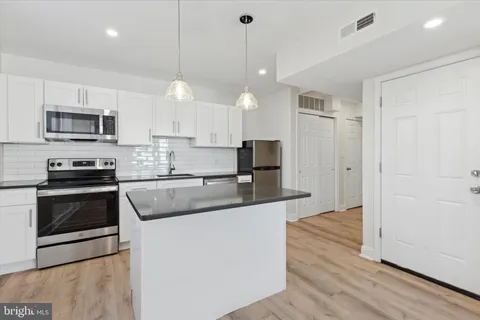 a kitchen with kitchen island a sink stainless steel appliances and cabinets