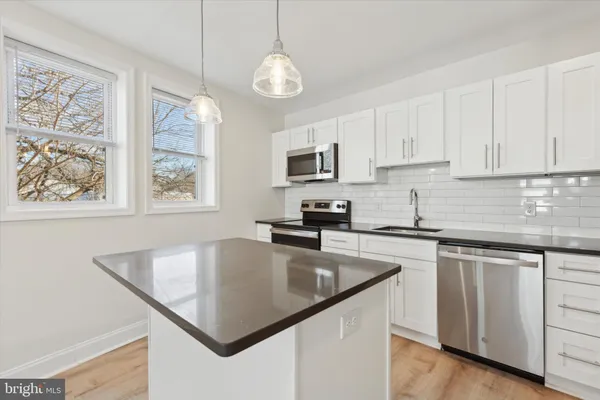 a kitchen with granite countertop a stove a sink dishwasher and a refrigerator with wooden floor