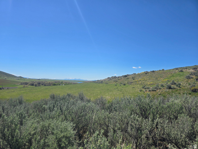8400 North Treasurton Road Preston, ID 83263 - Photo 2 of 13 Expansive natural landscape featuring rolling green hills and distant snow-capped mountains under a clear sky