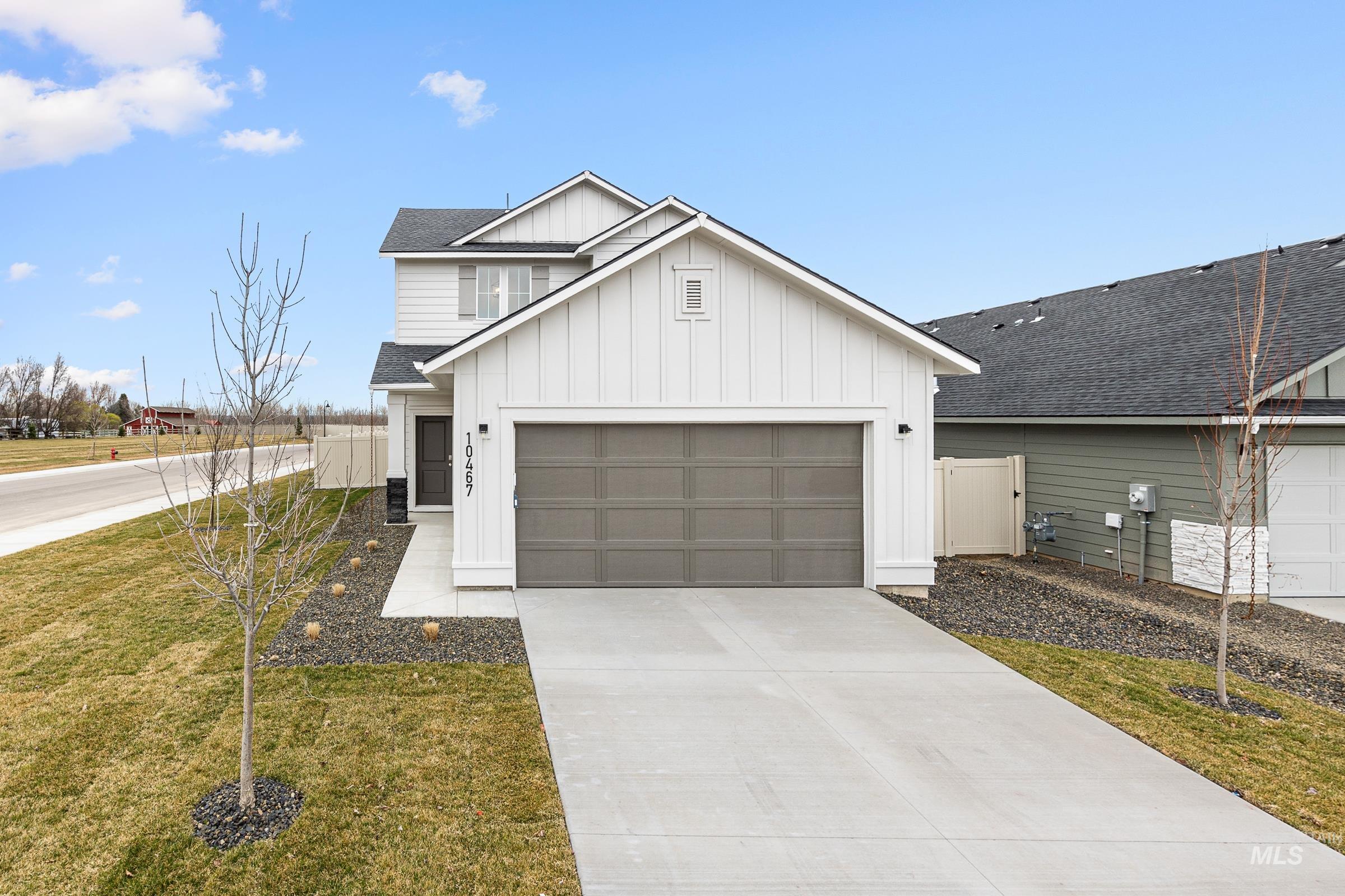 View of front of house featuring board and batten siding, roof with shingles, concrete driveway, and a garage