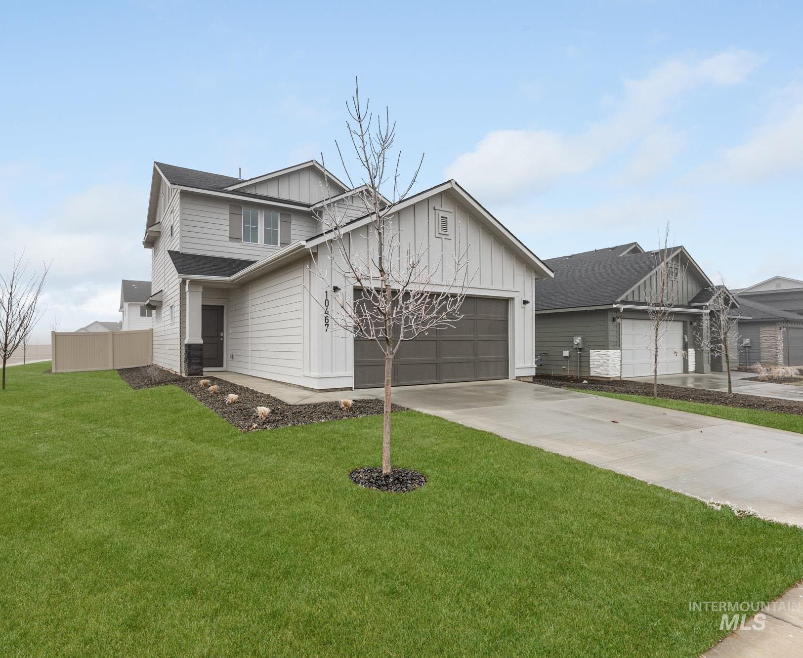 View of front of property with board and batten siding, driveway, and a garage