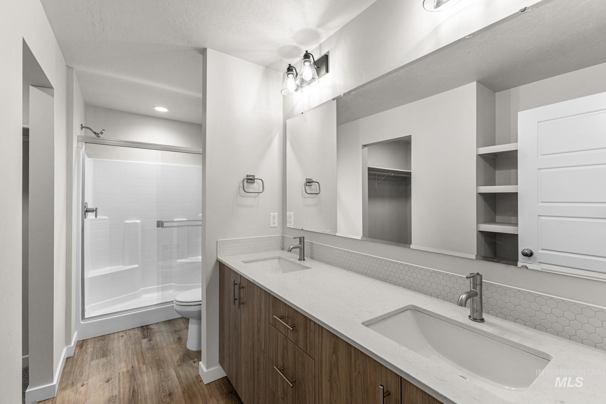 10467 West Tinder Street Star, ID 83669 - Photo 19 of 20 Bathroom featuring a shower with door, double vanity, dark wood-style floors, and a textured ceiling