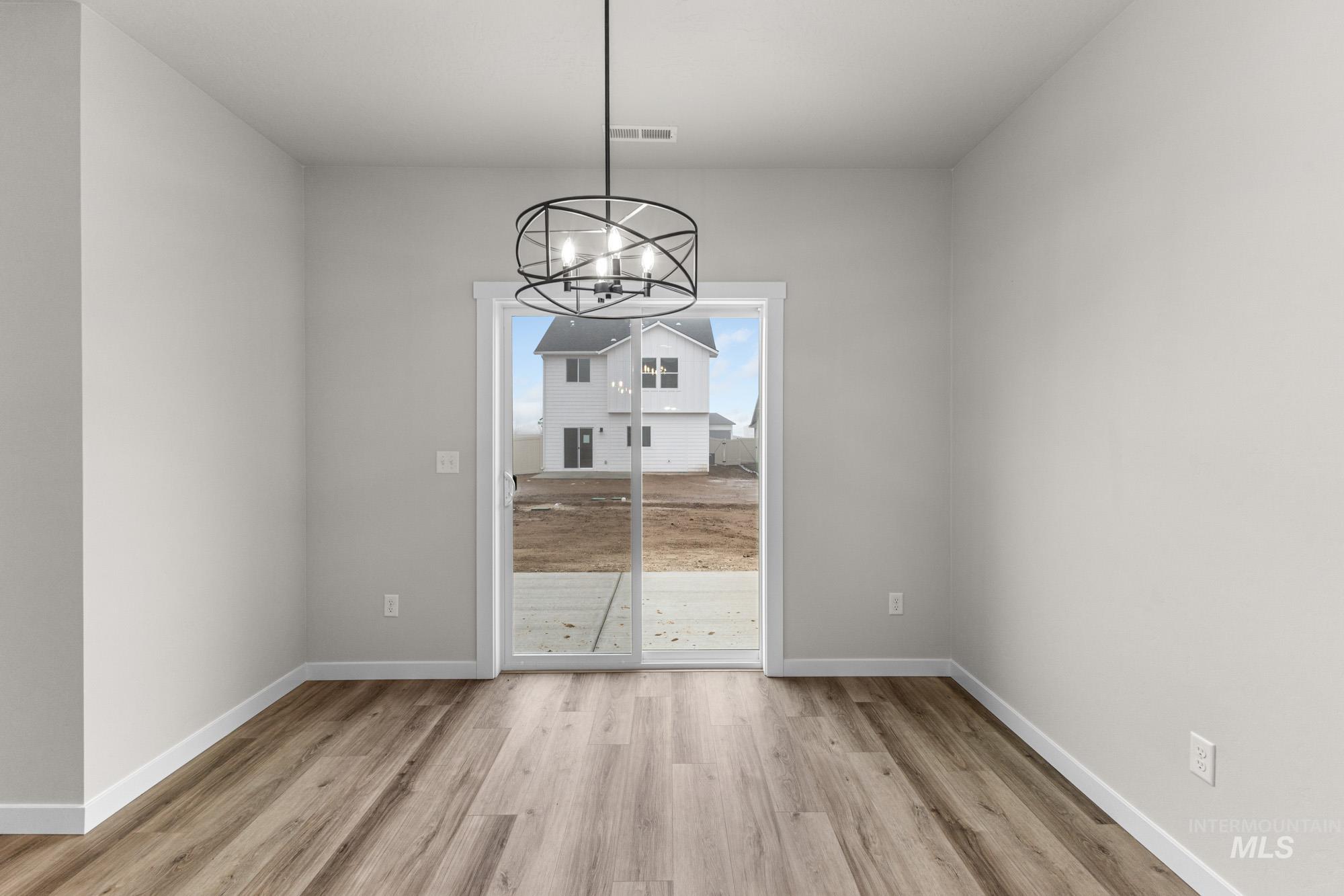 10467 West Tinder Street Star, ID 83669 - Photo 6 of 20 Unfurnished dining area with light wood-type flooring and a chandelier