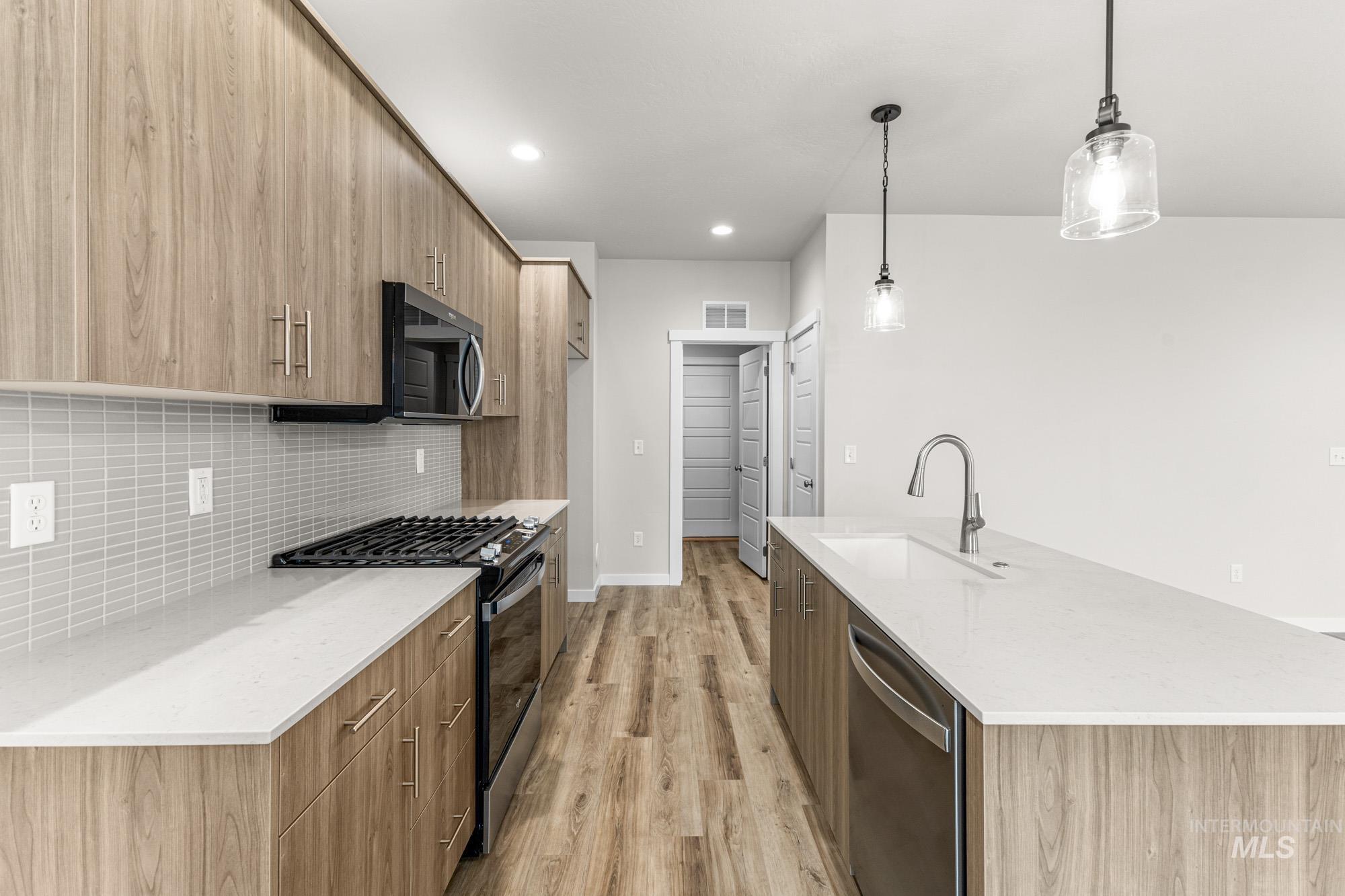 10467 West Tinder Street Star, ID 83669 - Photo 6 of 21 Kitchen with light stone counters, modern cabinets, appliances with stainless steel finishes, an island with sink, and recessed lighting