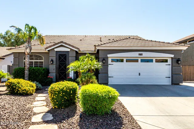a view of a white house with a large window and a yard with plants