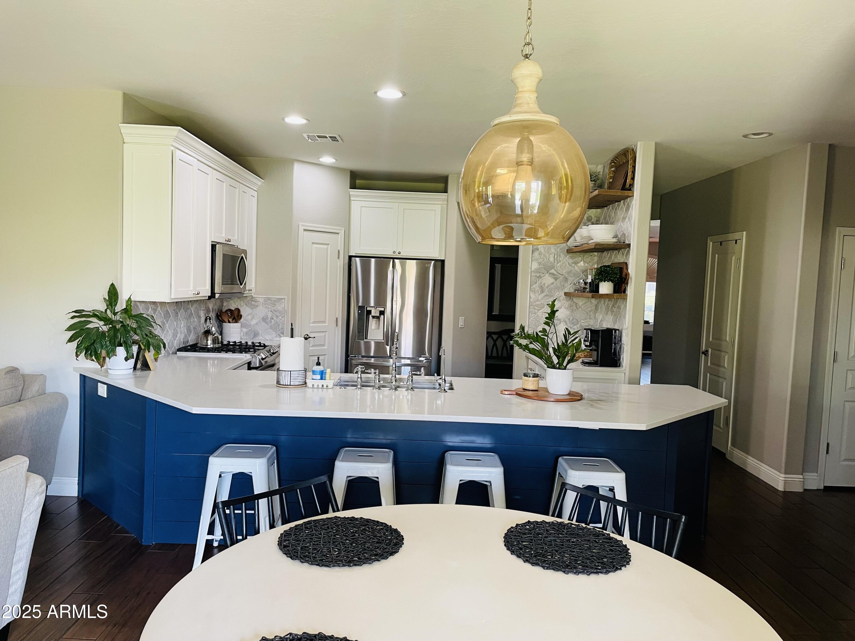 11411 East Sebring Circle Mesa, AZ 85212 - Photo 42 of 87 a kitchen with stainless steel appliances a table and chairs in it