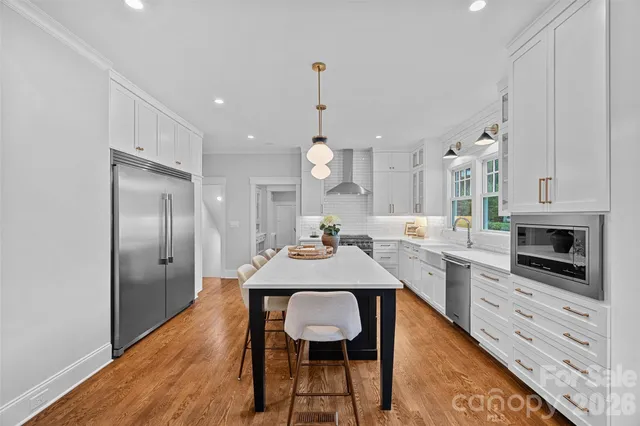 a kitchen with stainless steel appliances a dining table chairs stove and cabinets