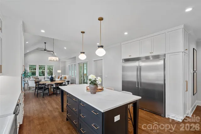 a kitchen with a refrigerator a sink dishwasher a dining table and chairs with wooden floor