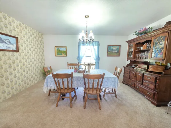 a dining room with wooden floor a chandelier a wooden table and chairs