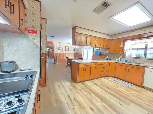 a large kitchen with stainless steel appliances wooden cabinets a center island and a stove top oven
