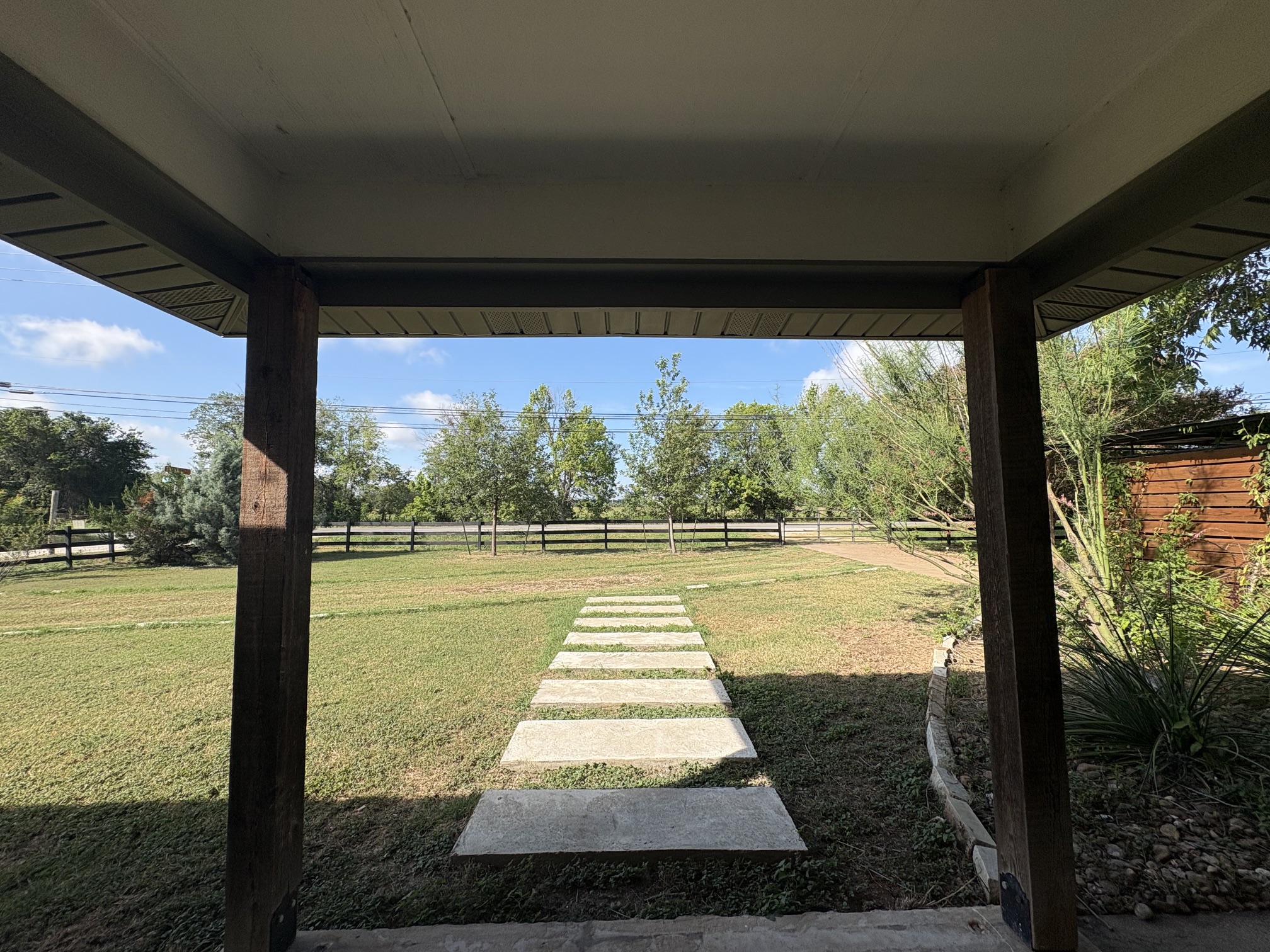9032 Nuckols Crossing Road Austin, TX 78744 - Photo 2 of 14 A stone pathway guides you through the well-maintained yard, bordered by a classic wooden fence.