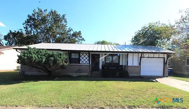 a front view of house with yard and trees in the background