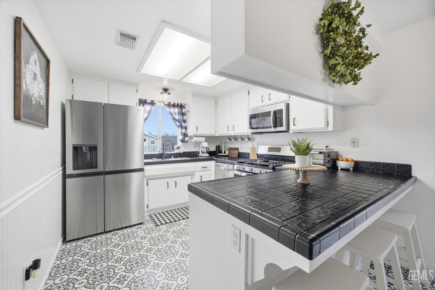 Undisclosed Address Tehachapi, CA 93561 - Photo 10 of 46 a kitchen with a refrigerator a stove a microwave and center island