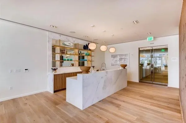 a large room with kitchen island wooden floor and stainless steel appliances