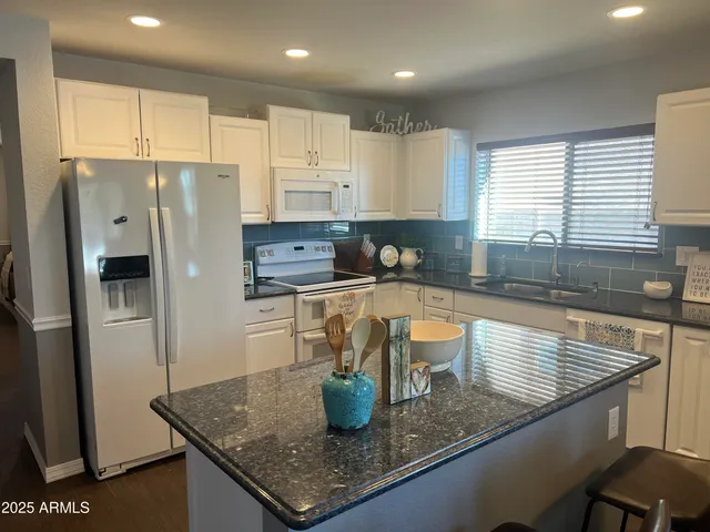 a kitchen with stainless steel appliances granite countertop a sink a refrigerator and a granite counter tops