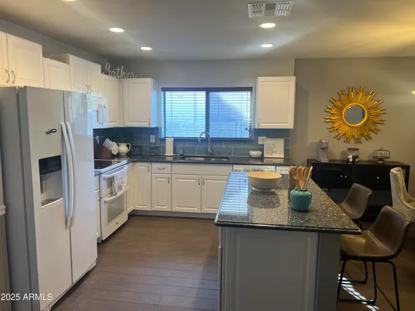 a kitchen with stainless steel appliances granite countertop a sink a stove a refrigerator cabinets and a dining table