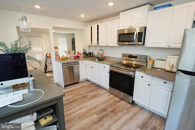 a kitchen with stainless steel appliances granite countertop a stove top oven a sink dishwasher and a microwave with wooden floor