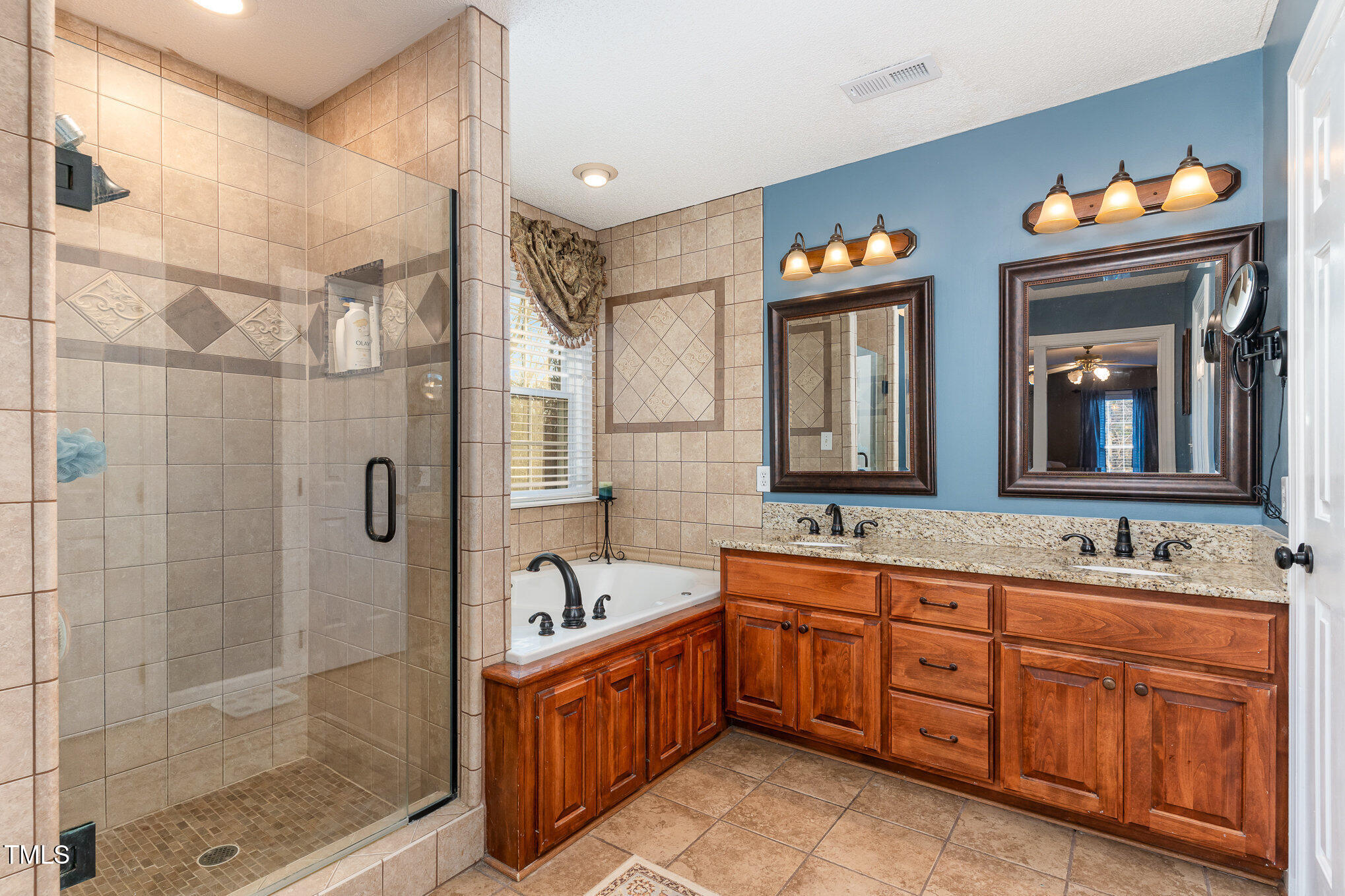 6132 Wolverhampton Drive Raleigh, NC 27603 - Photo 19 of 40 a spacious bathroom with double vanity a mirror a shower and a bathtub