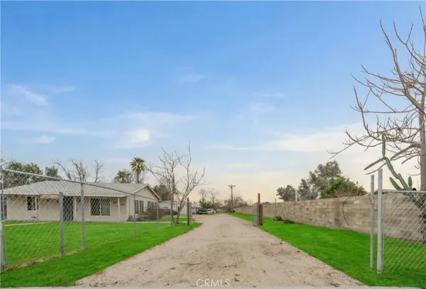 a view of a street with a big yard and large trees