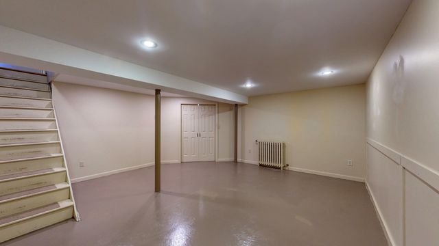 a view of an empty room with stairs and a window