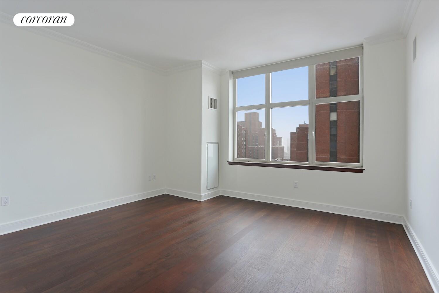 181 East 90th Street, Unit 25B Manhattan, NY 10128 - Photo 5 of 9 an empty room with wooden floor and windows