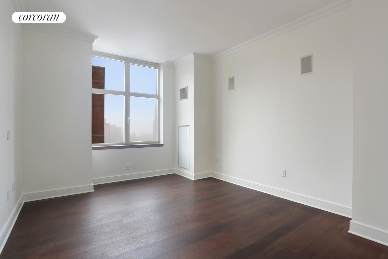181 East 90th Street, Unit 25B Manhattan, NY 10128 - Photo 6 of 9 an empty room with wooden floor and windows