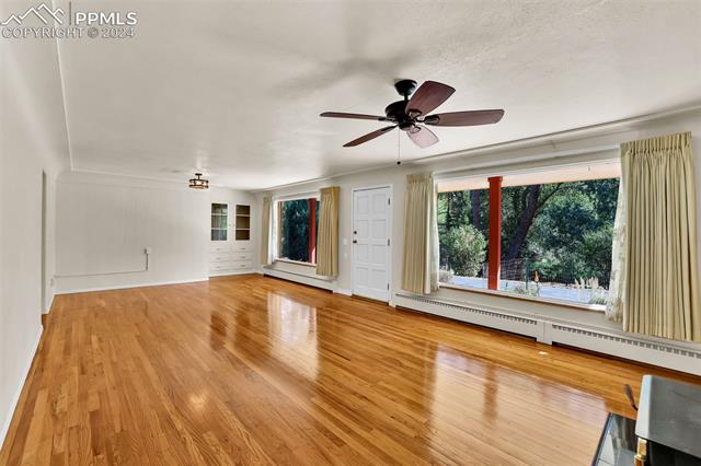 1404 West Cheyenne Road Colorado Springs, CO 80906 - Photo 21 of 50 Unfurnished living room with ceiling fan, a baseboard radiator, and hardwood / wood floors