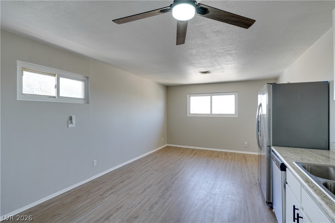 247 West Basic Road, Unit B Henderson, NV 89015 - Photo 2 of 7 A well-lit interior space with sleek wood flooring extends towards a modern kitchen area.