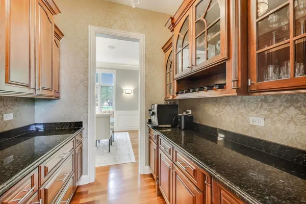 a kitchen with stainless steel appliances granite countertop a stove top oven a sink dishwasher a dining table and chairs with wooden floor