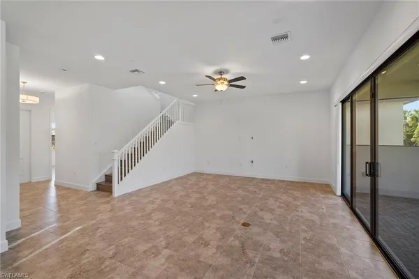 a view of an empty room with a ceiling fan and window