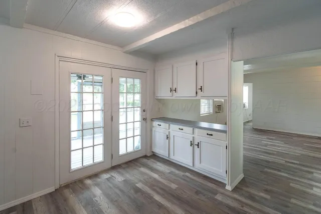 a kitchen with granite countertop white cabinets and wooden floor