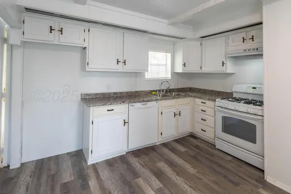 a kitchen with granite countertop white cabinets and white appliances