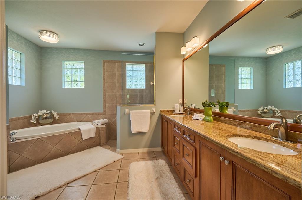 186 Muirfield Circle Naples, FL 34113 - Photo 18 of 36 a spacious bathroom with a double vanity sink a mirror and a bathtub
