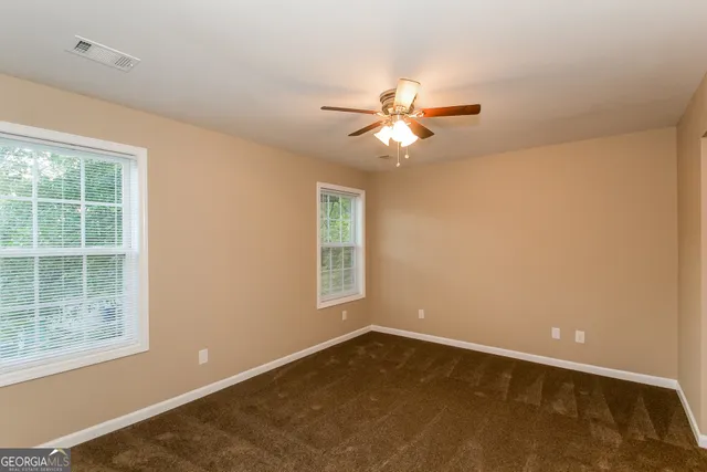 an empty room with a window and a fan