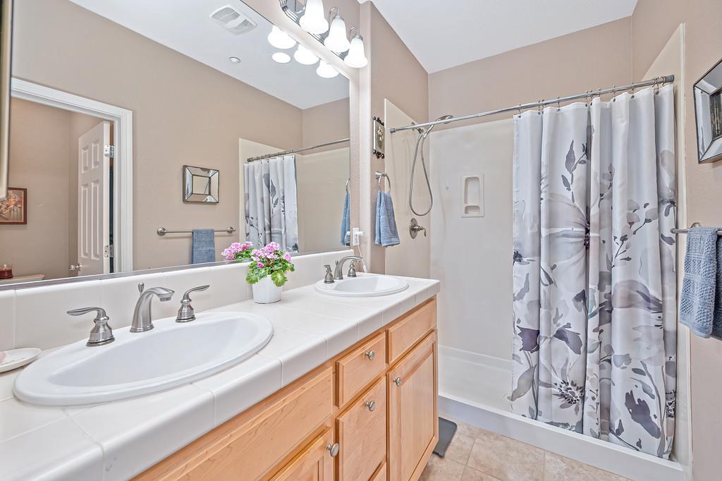 2603 Las Palomas Loop Lincoln, CA 95648 - Photo 17 of 22 a bathroom with a granite countertop sink a mirror a vanity and a shower