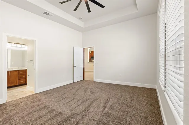 an empty room with chandelier fan and windows